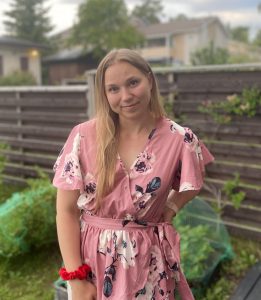 Blonde girl with pink flowery dress standing in a garden
